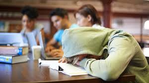 A student covered by a hood sleeping while studying.